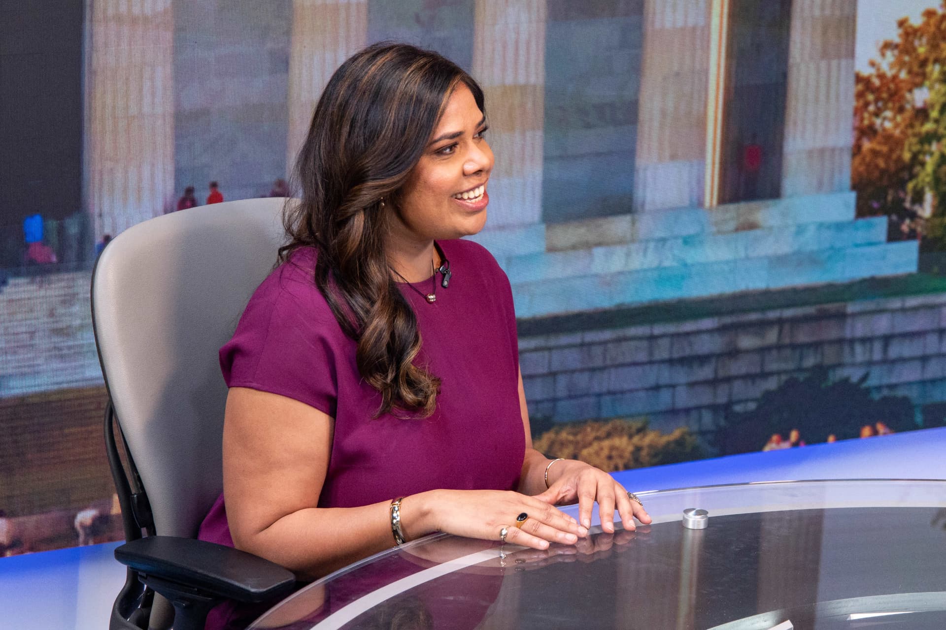 Khushi Yadav smiling at the anchor desk of a TV news set in Washington, D.C.
