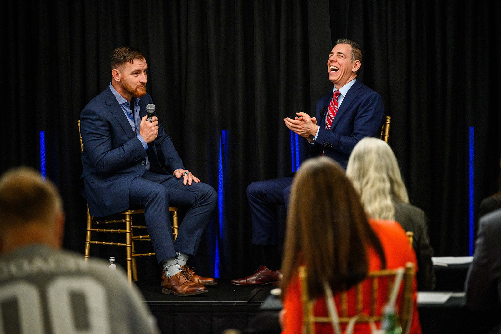 Mark Albert laughing during a live stage conversation with a guest